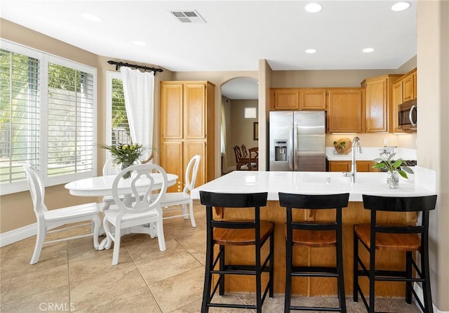 kitchen featuring a breakfast bar, kitchen peninsula, sink, stainless steel appliances, and light tile patterned floors