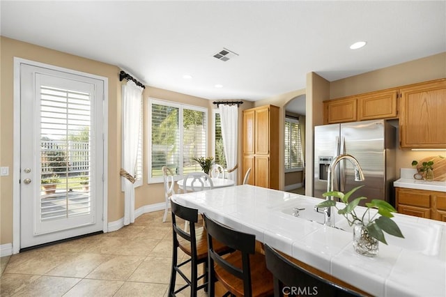 kitchen featuring light tile patterned floors, tile countertops, and stainless steel fridge