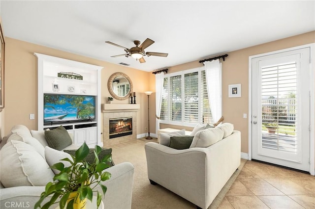 tiled living room featuring ceiling fan, a fireplace, and a wealth of natural light