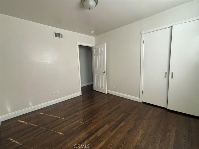 unfurnished bedroom featuring dark hardwood / wood-style flooring and a closet