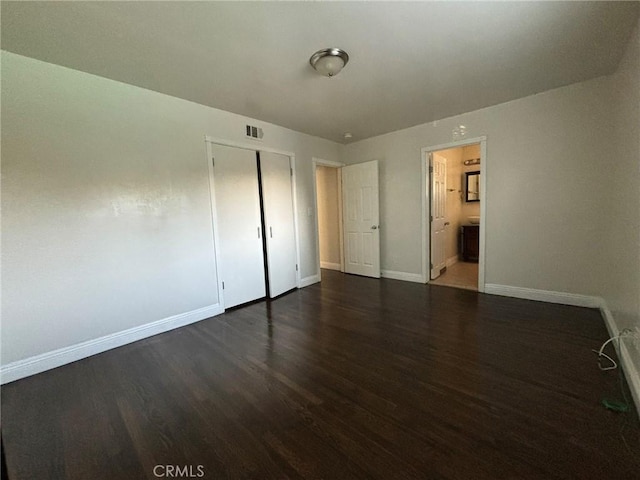 unfurnished bedroom with dark hardwood / wood-style flooring, connected bathroom, and a closet