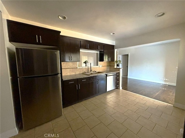 kitchen with dark brown cabinetry, appliances with stainless steel finishes, sink, and backsplash