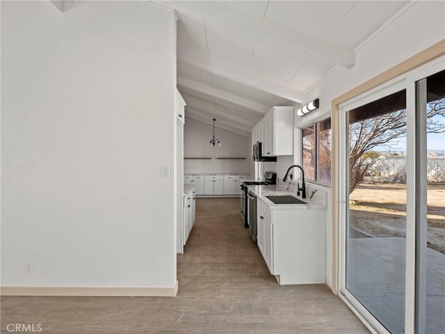 kitchen with vaulted ceiling with beams, appliances with stainless steel finishes, sink, and white cabinetry