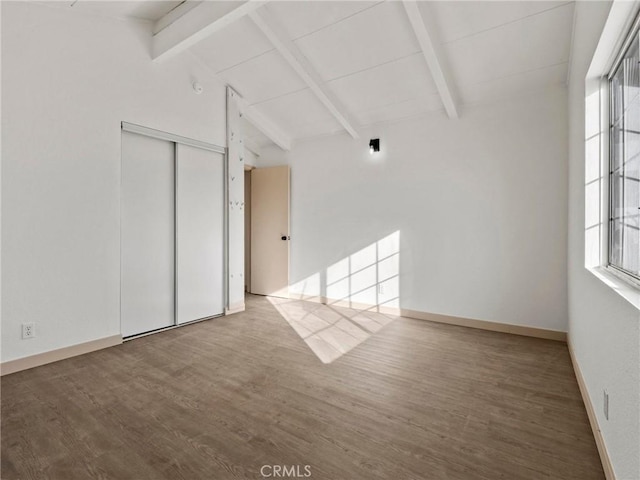 spare room with hardwood / wood-style flooring and vaulted ceiling with beams