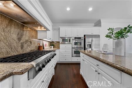 kitchen featuring premium range hood, white cabinetry, stainless steel appliances, and dark stone counters