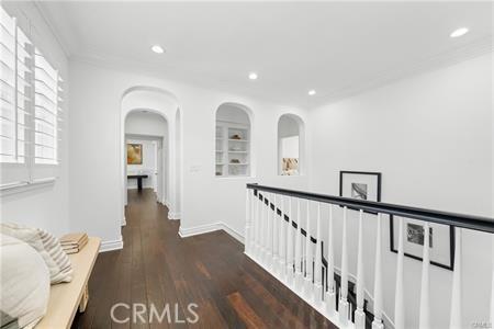 hall featuring crown molding, dark hardwood / wood-style floors, and built in shelves