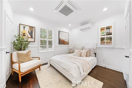 bedroom with dark hardwood / wood-style floors and a wall unit AC