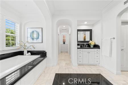 bathroom with a bathing tub, ornamental molding, tile patterned floors, and vanity