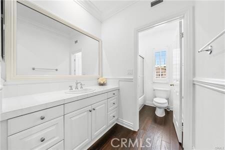 bathroom with toilet, crown molding, hardwood / wood-style floors, and vanity