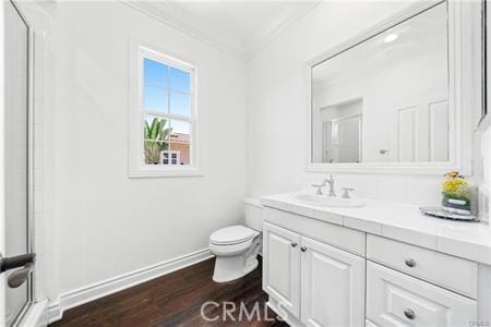 bathroom featuring toilet, vanity, hardwood / wood-style floors, crown molding, and a shower with shower door