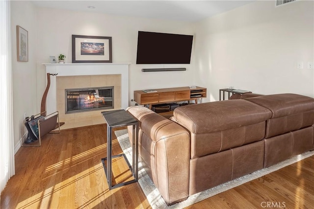 living room featuring a tiled fireplace and light hardwood / wood-style floors