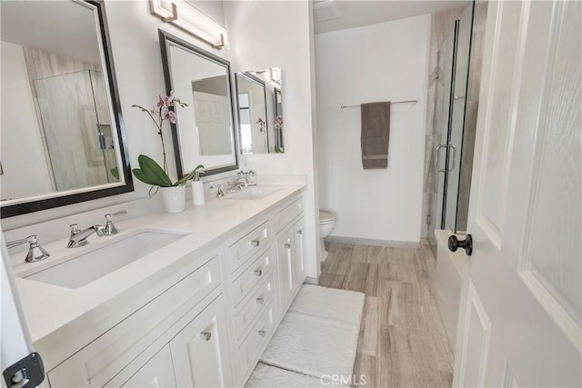 bathroom featuring vanity, wood-type flooring, toilet, and walk in shower