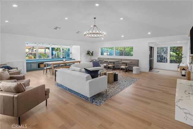 living room featuring a healthy amount of sunlight, an inviting chandelier, and light hardwood / wood-style flooring