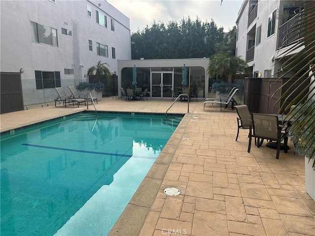 community pool with a patio area and fence