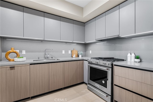 kitchen with light brown cabinetry, gas range, ventilation hood, and sink