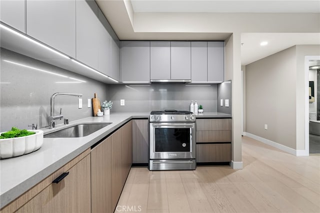 kitchen with gas stove, light hardwood / wood-style floors, sink, white cabinets, and light brown cabinetry