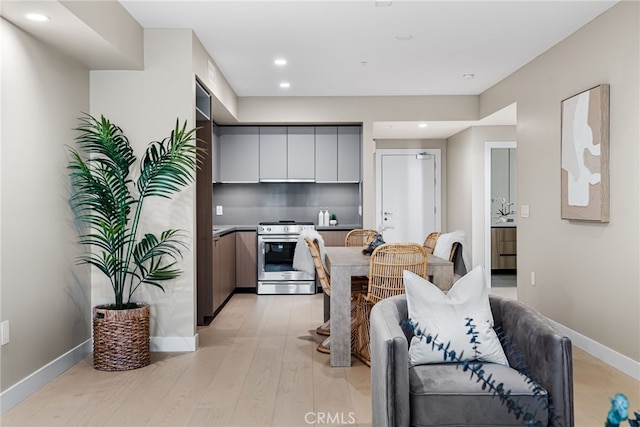 kitchen featuring stainless steel range oven, light hardwood / wood-style floors, and tasteful backsplash