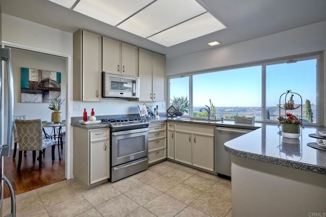 kitchen featuring light tile patterned floors, stainless steel appliances, dark stone counters, and sink