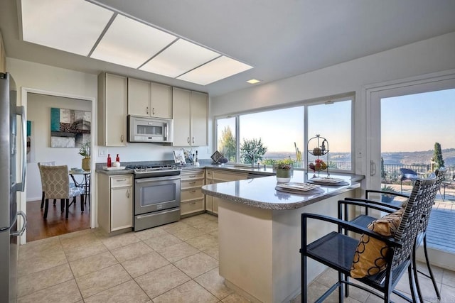 kitchen with kitchen peninsula, sink, appliances with stainless steel finishes, and light tile patterned flooring