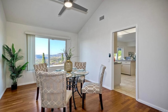 dining space featuring ceiling fan, lofted ceiling, and light wood-type flooring