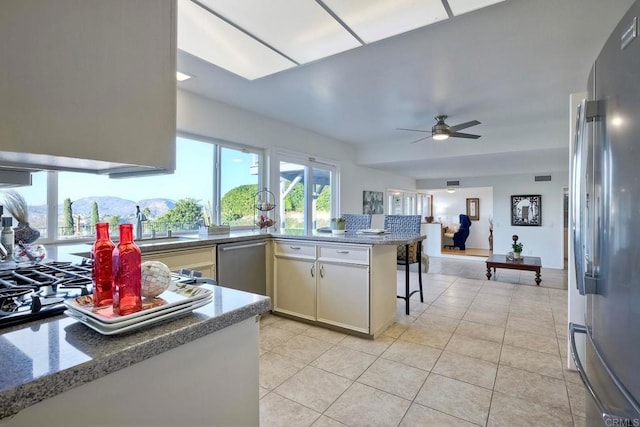 kitchen featuring appliances with stainless steel finishes, ceiling fan, kitchen peninsula, a mountain view, and a breakfast bar