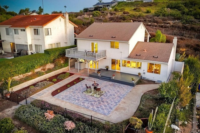 back of house with a balcony, a patio area, and a fire pit