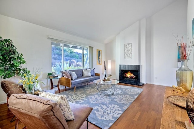 living room featuring a brick fireplace, lofted ceiling, and hardwood / wood-style flooring