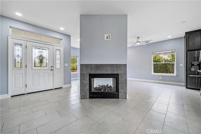 tiled entryway featuring ceiling fan and a fireplace