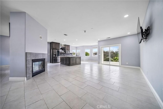 unfurnished living room featuring light tile patterned floors and a tiled fireplace