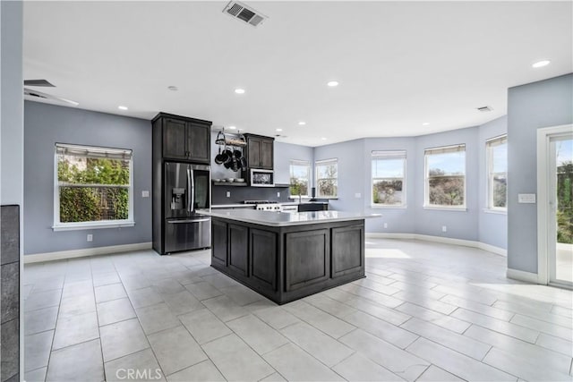 kitchen featuring ceiling fan, dark brown cabinets, appliances with stainless steel finishes, and a kitchen island with sink