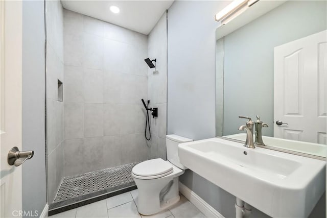 bathroom with toilet, tile patterned flooring, sink, and a tile shower