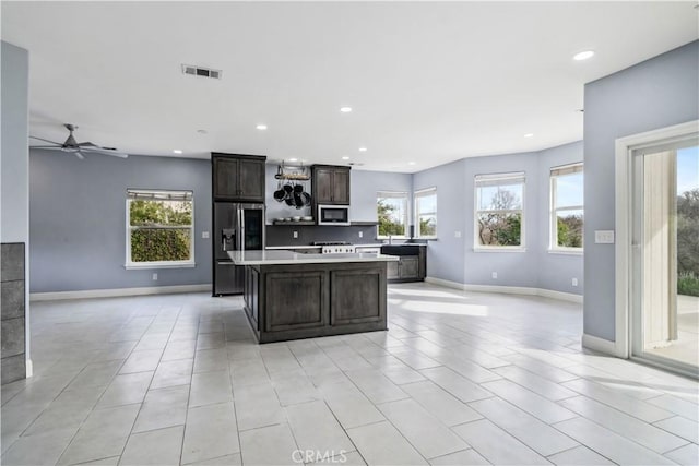 kitchen featuring ceiling fan, dark brown cabinetry, appliances with stainless steel finishes, and a center island