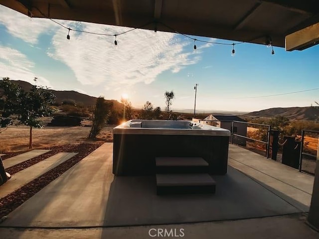 patio terrace at dusk featuring a mountain view and a hot tub