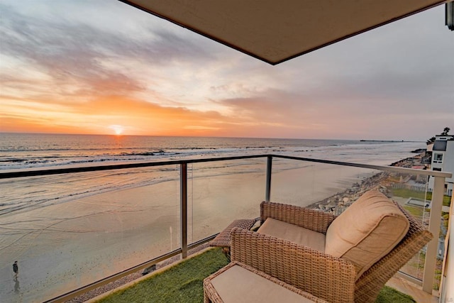 balcony at dusk with a water view and a beach view