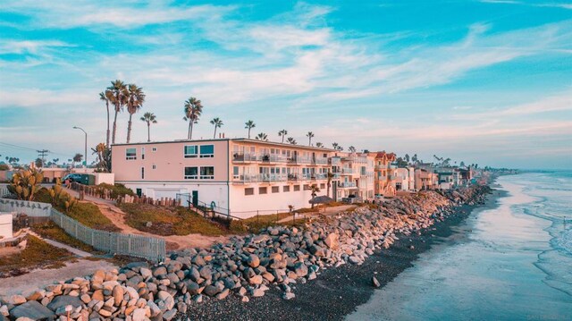 view of building exterior featuring a water view and a beach view