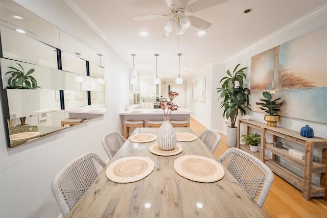 dining room with ceiling fan, ornamental molding, and light hardwood / wood-style flooring