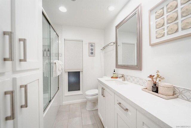 full bathroom with toilet, bath / shower combo with glass door, tile patterned floors, and vanity