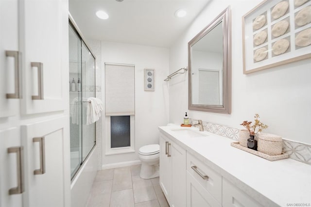 full bathroom with bath / shower combo with glass door, toilet, vanity, and tile patterned flooring