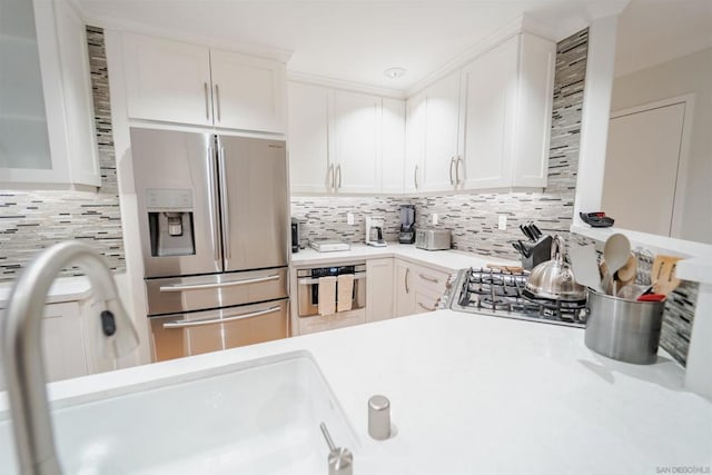 kitchen featuring tasteful backsplash, white cabinets, appliances with stainless steel finishes, and sink