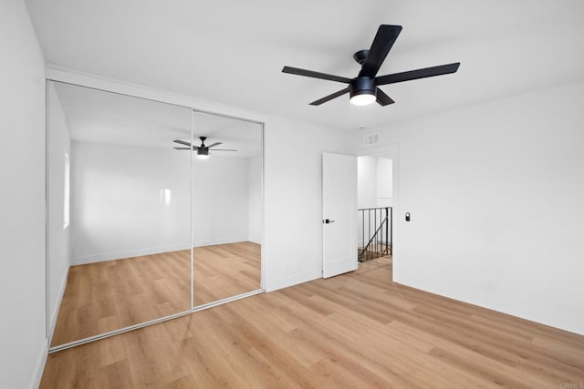 unfurnished bedroom featuring ceiling fan, a closet, and light hardwood / wood-style flooring