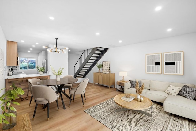 living room featuring light wood-type flooring, sink, and an inviting chandelier