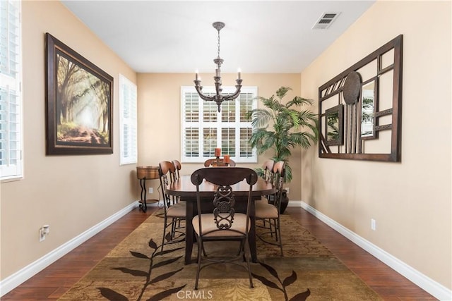 dining area with a healthy amount of sunlight, dark hardwood / wood-style flooring, and a chandelier