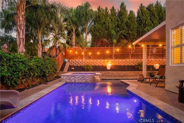 pool at dusk with an in ground hot tub and a patio