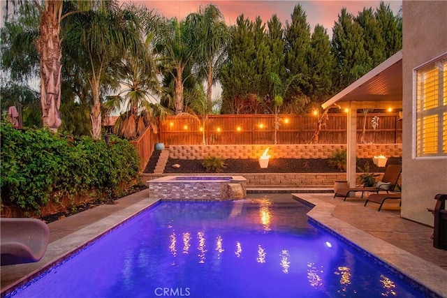 pool at dusk with a patio, a water slide, a fenced backyard, an in ground hot tub, and a fenced in pool