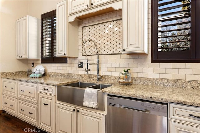 kitchen featuring light stone countertops, dishwasher, sink, and tasteful backsplash