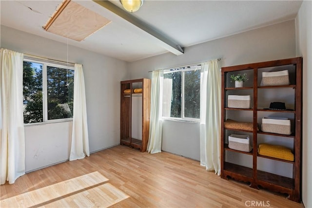 unfurnished bedroom with wood-type flooring and beamed ceiling