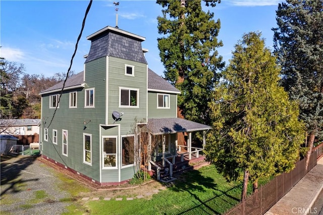 rear view of property featuring covered porch and a yard