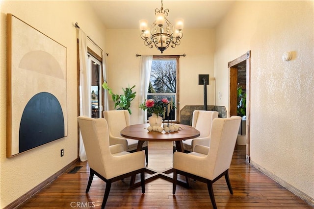 dining space featuring a wood stove, dark hardwood / wood-style floors, and an inviting chandelier