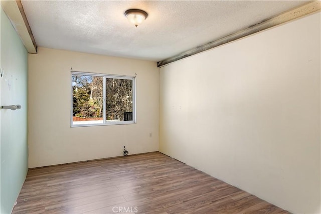 empty room featuring a textured ceiling and light hardwood / wood-style floors