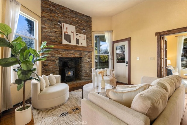 living room with a wealth of natural light, a wood stove, and hardwood / wood-style floors